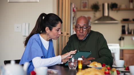 a healthcare professional discussing a patient's medical records with an elderly man in his home