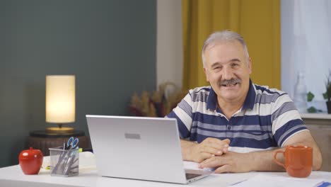 trabajador de oficina en casa anciano hablando en facetime mirando a la cámara.