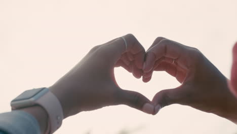 가까운 여자 손은 해가 지는 동안 심장 모양의 몸짓을 하는 사랑에 빠진 십대 소녀 발렌타인 데이 개념