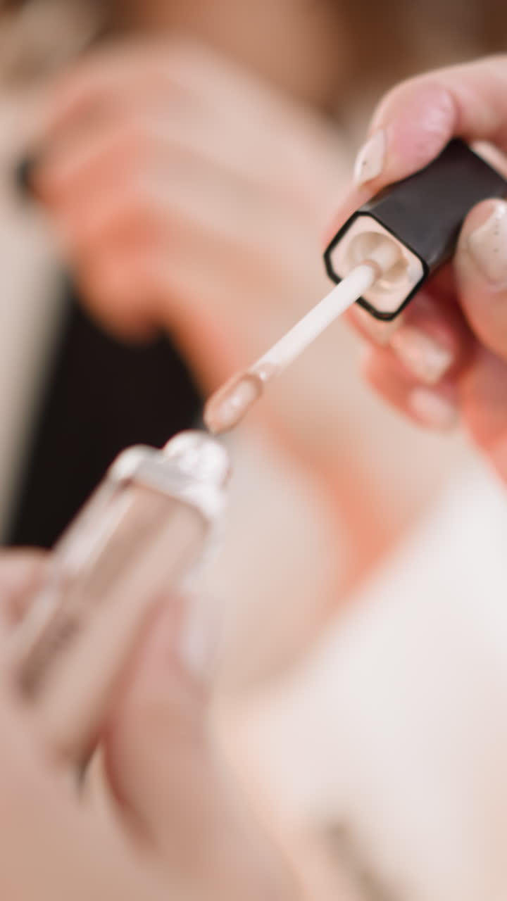 Hands of woman unrolling beige concealer to apply on skin under eyes on blurred background. Lady uses foundation to prepare face for makeup closeup