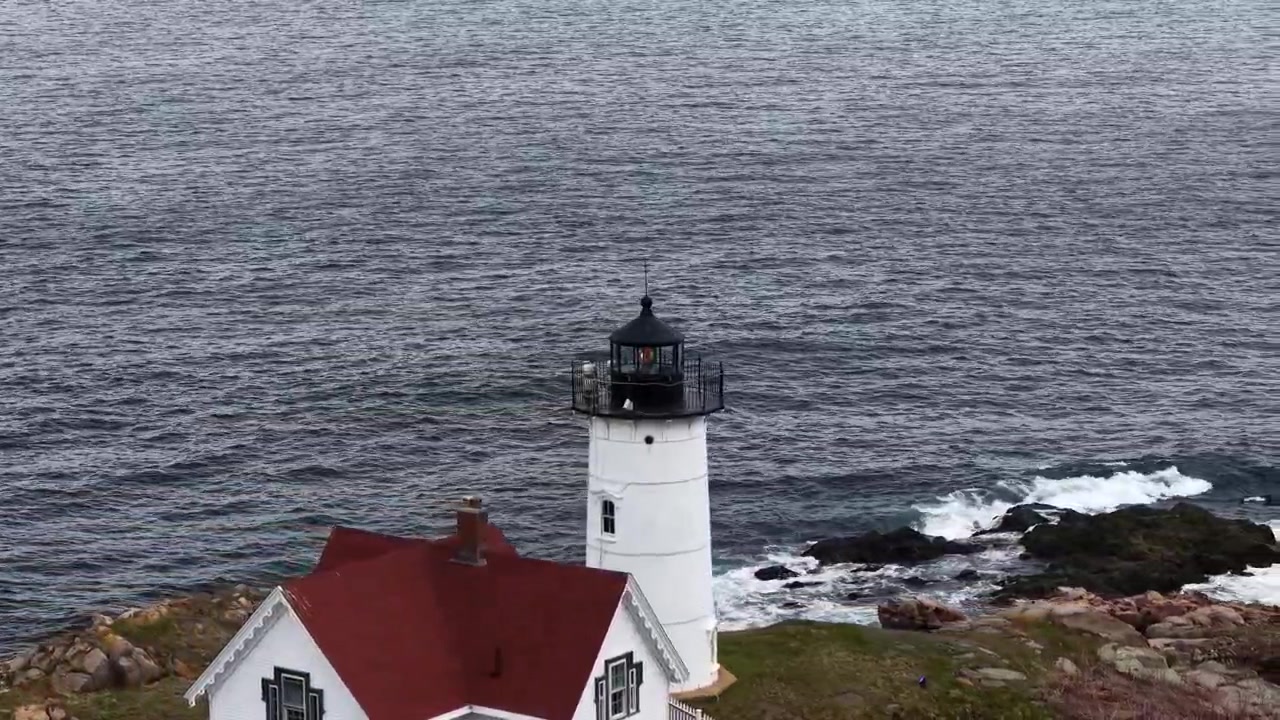 Pemandangan drone udara mercusuar Portland Head Light dan rumah penjaga di samping garis pantai Atlantik yang berbatu dengan ombak laut di Maine, Amerika Serikat