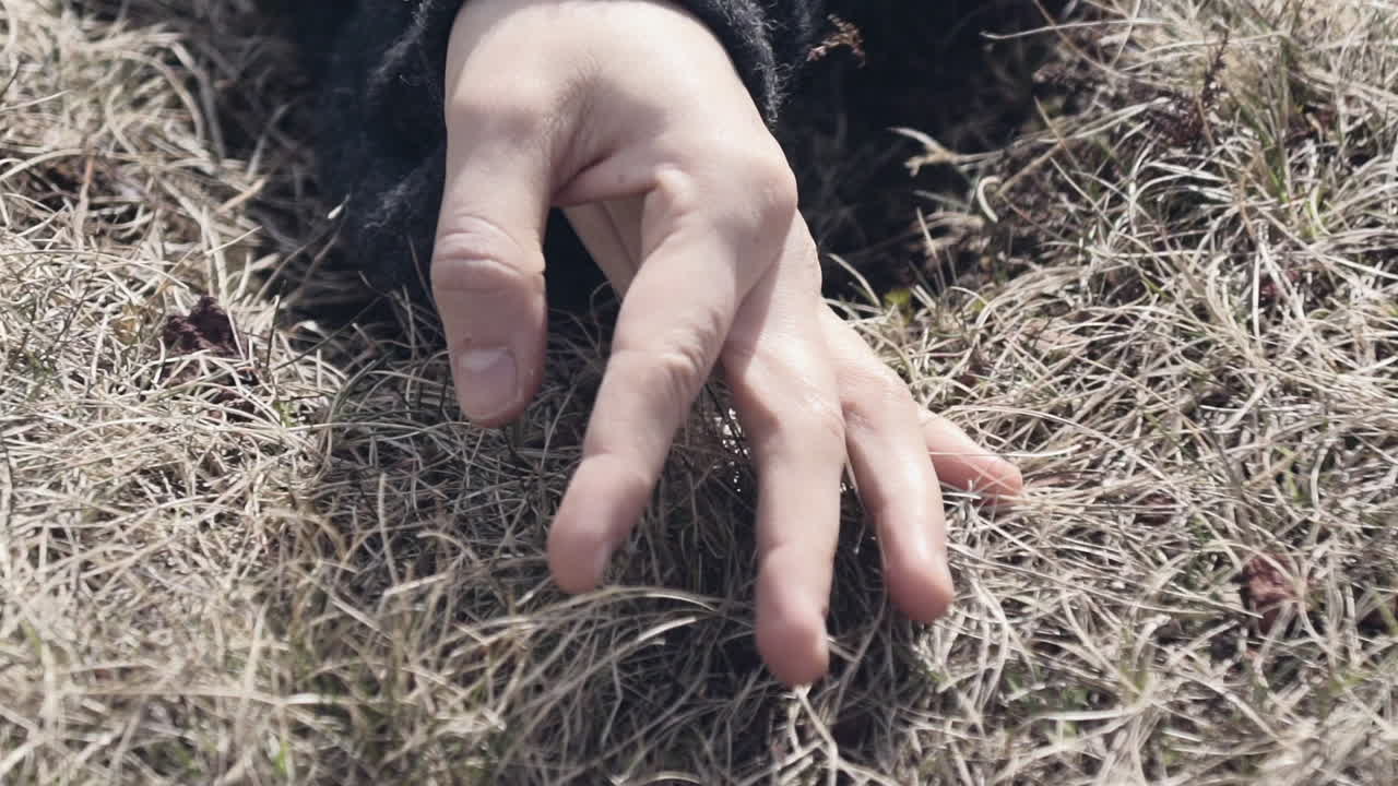 Close-up of a woman's hand sensually touching grass