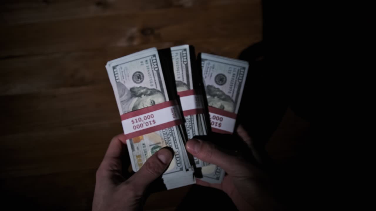 Male Hands Hold Three Stacks of 10000 US Dollar Bills on Wooden Background