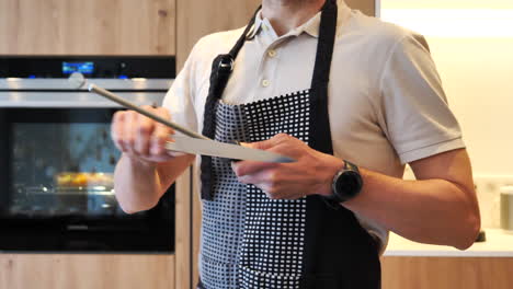 unrecognizable male chef in kitchen sharpening knife with honing rod