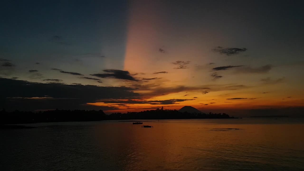 video panorámico en cámara lenta de una hermosa puesta de sol con un volcán en el fondo