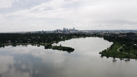 drone shot pulling away from sloan lake with denver, colorado in the backdrop