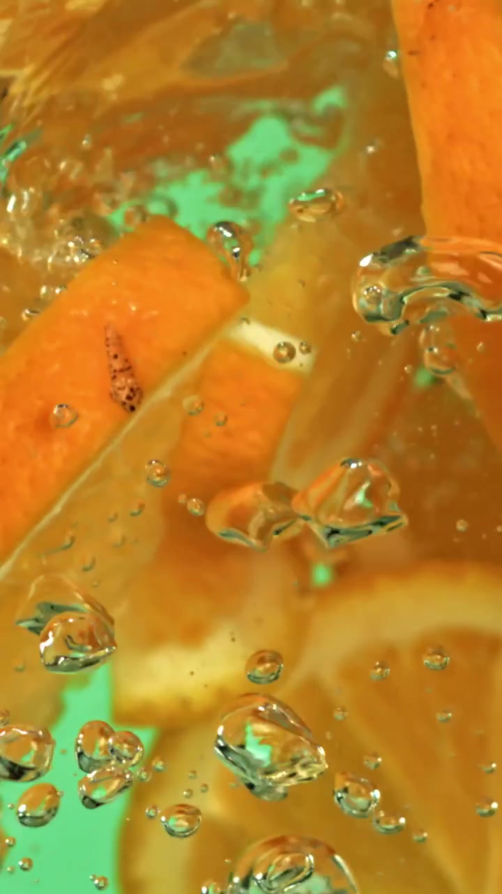 Fette d'arancia fresche che cadono in acqua con bolle