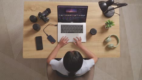 top view of a woman color grading celebrating succeed using a laptop next to the camera editing the video in the workspace at home