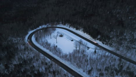 drone video at dusk in the mountains with cars driving around a hairpin