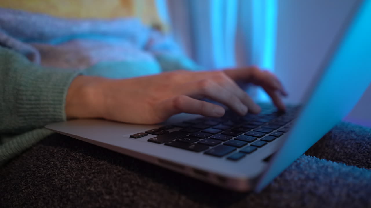 escribiendo en la computadora por la noche, mientras está sentado en la cama