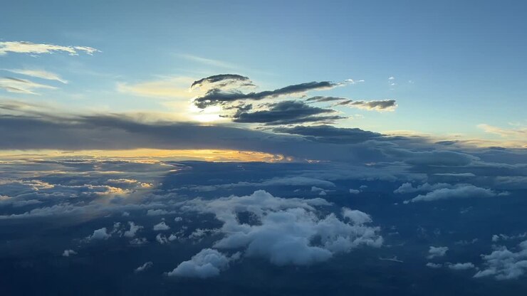 Smuk solnedgang med overskyet himmel set fra et cockpit.