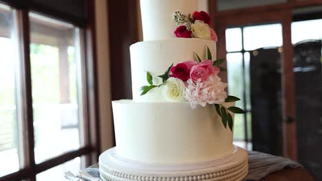 triple tiered wedding cake with beautiful flowers and white frosting, close-up