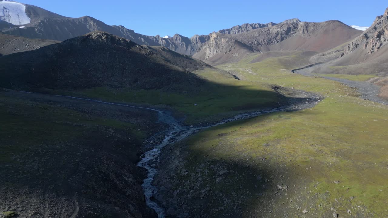 Solitary tent beneath a vast alpine pass in the distance
