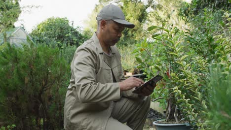 Mixed-race-male-gardener-using-tablet-at-garden-center