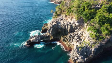 Video-Aéreo-Cinematográfico-De-Una-Isla-Tropical-Con-Olas-De-Agua-Turquesa-Aplastando-Acantilados-Rocosos,-Playa-De-La-Bahía-De-Cristal,-Nusa-Penida,-Bali,-Indonesia,-Vista-Aérea-De-Arriba-Hacia-Abajo