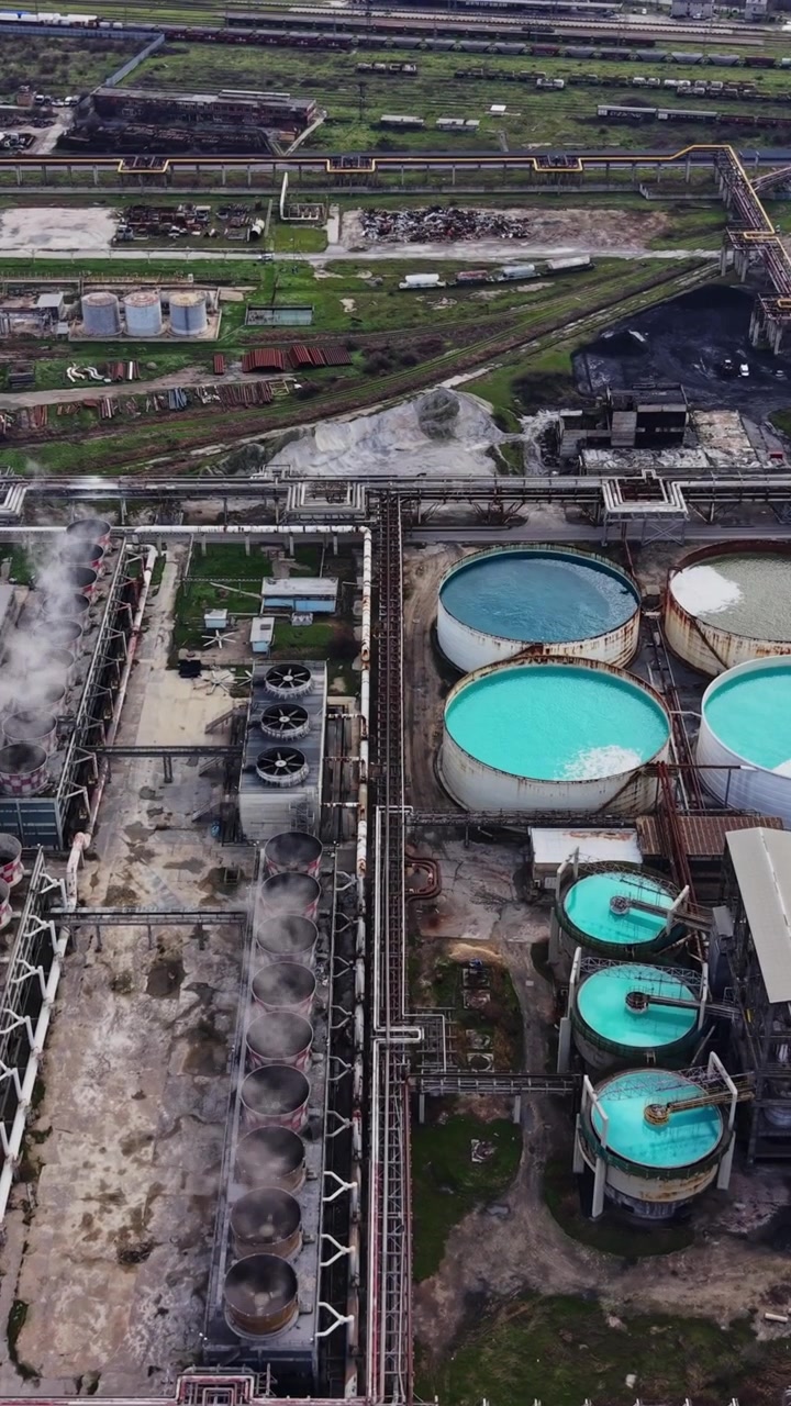 Industrial site with tanks and pipes near coastal area in broad daylight