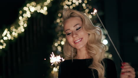 a young woman admires the sparklers in her hands