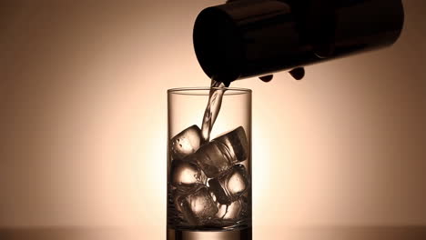 pouring a cocktail into a glass with ice cubes
