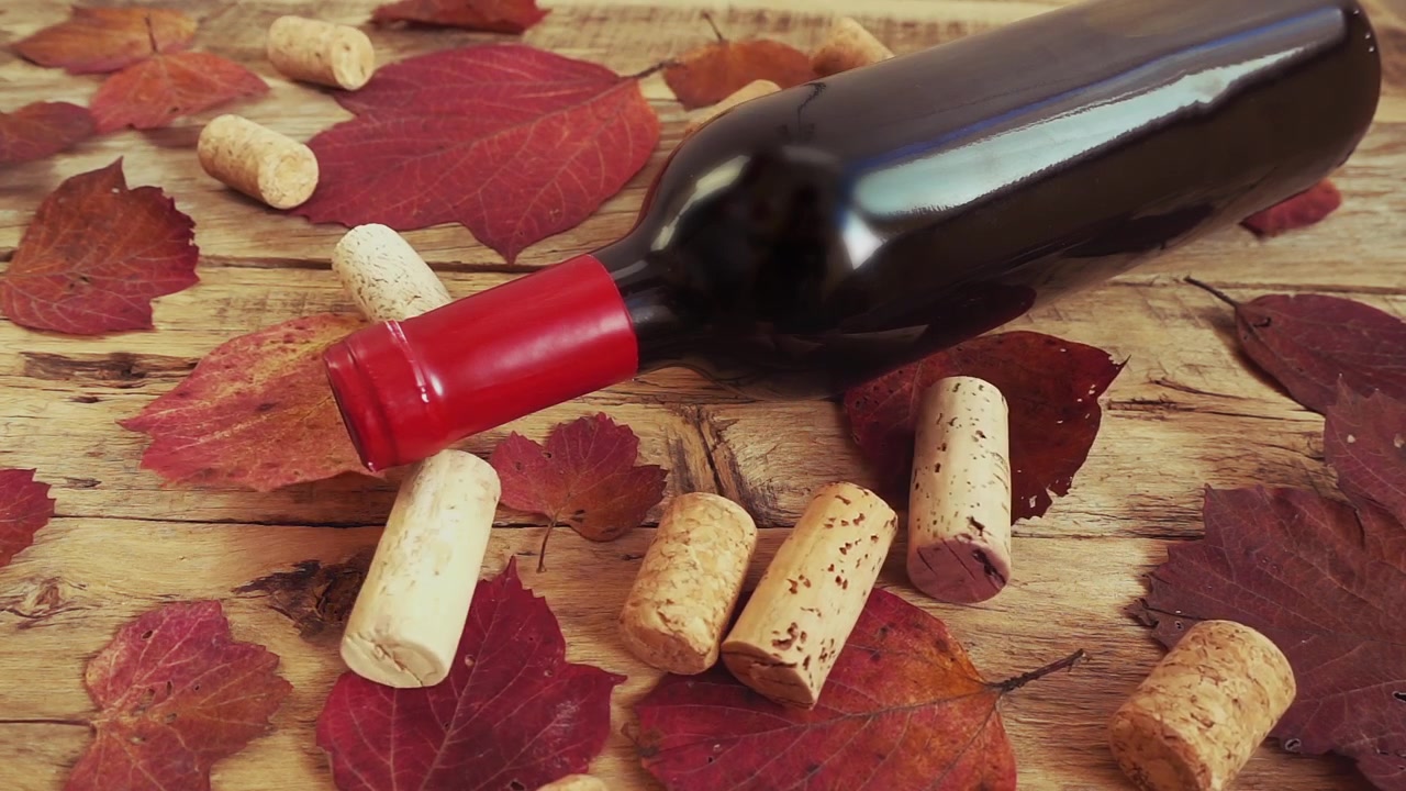Botellas de vino sobre una antigua tabla de madera vintage y corchos cayendo. En cámara lenta.