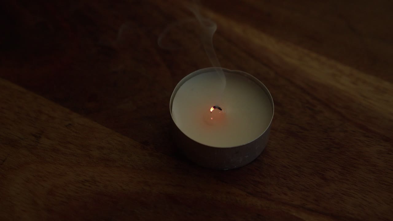 Wick of tea light smokes after candle is blown out, close up view
