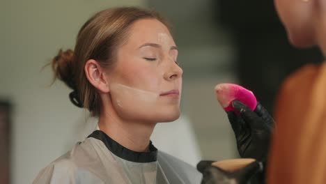 close-up of young woman getting makeup done by professional makeup artist