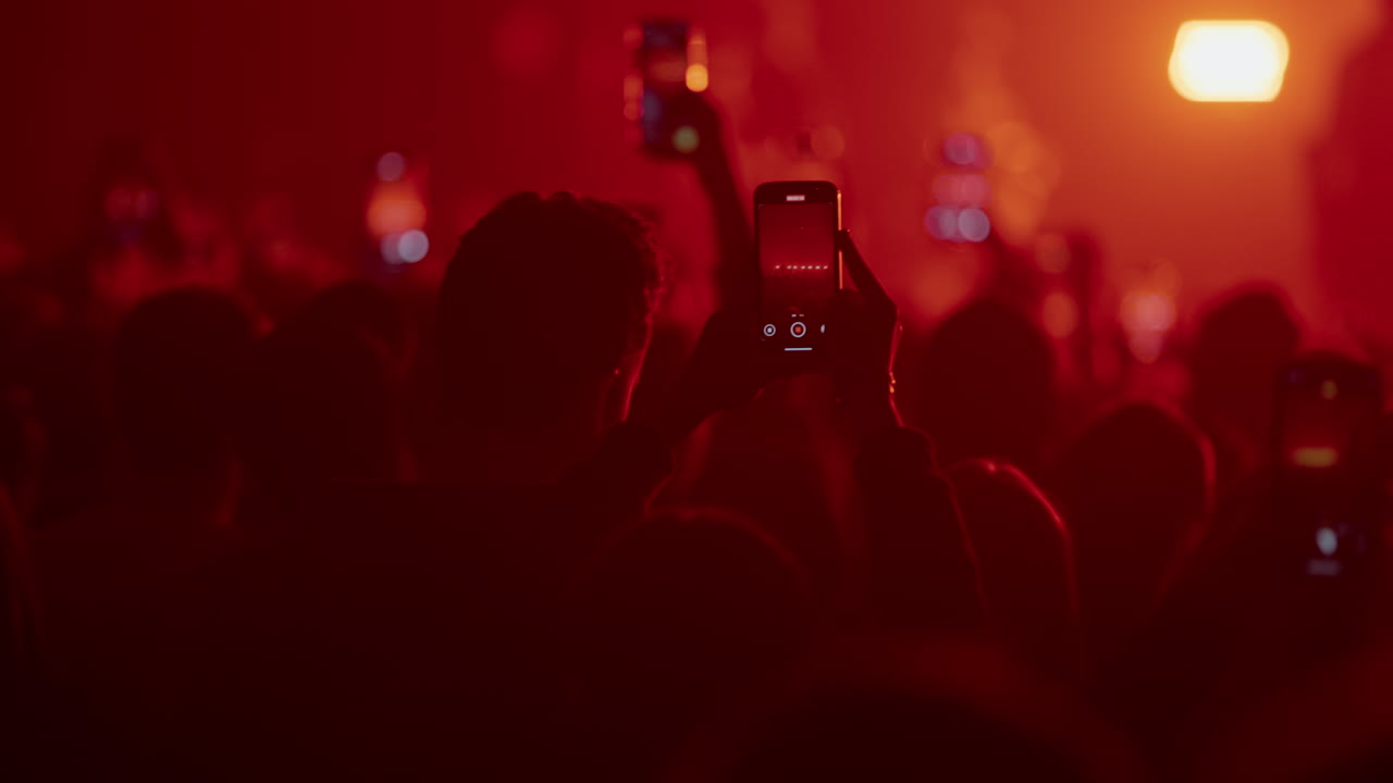 Folla a un concerto con telefoni illuminati di rosso