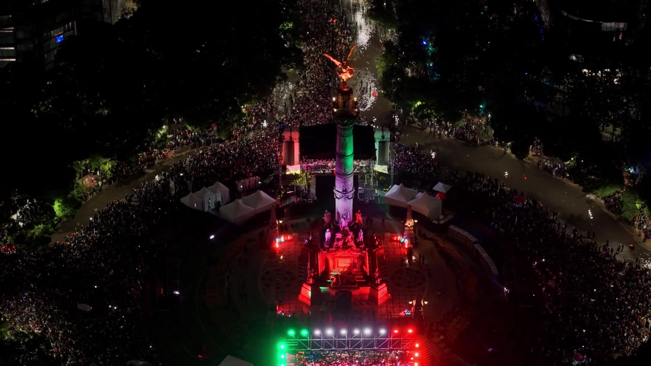 Vista aérea en picado del Monumento a la Independencia de la Ciudad de México de noche, lleno de gente celebrando la victoria de México en la Copa del Mundo de 2026
