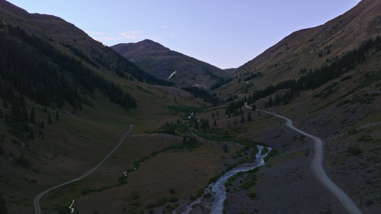 Široký záběr dronem na údolí American Basin s pletencovým potokem a okolními horskými svahy, záběr s oddálením.