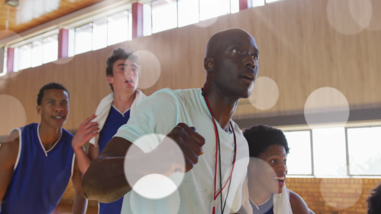 Animation of light spots over diverse male basketball team screaming with joy