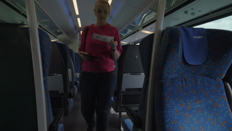 Shot-of-young-blond-woman-going-along-train-and-searching-her-seat-place-modern-rail-train-Vienna-Austria