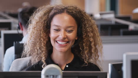 businesswoman wearing telephone headset talking to caller in customer services department