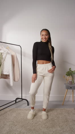 video vertical editado con cortes de salto de una influencer femenina de redes sociales produciendo contenido generado por el usuario en el estudio modelando diferentes trajes de moda 2