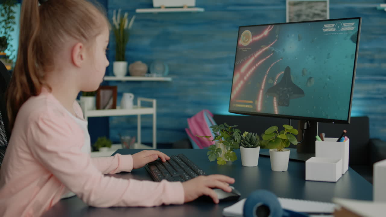 Young girl playing video games on computer after online school