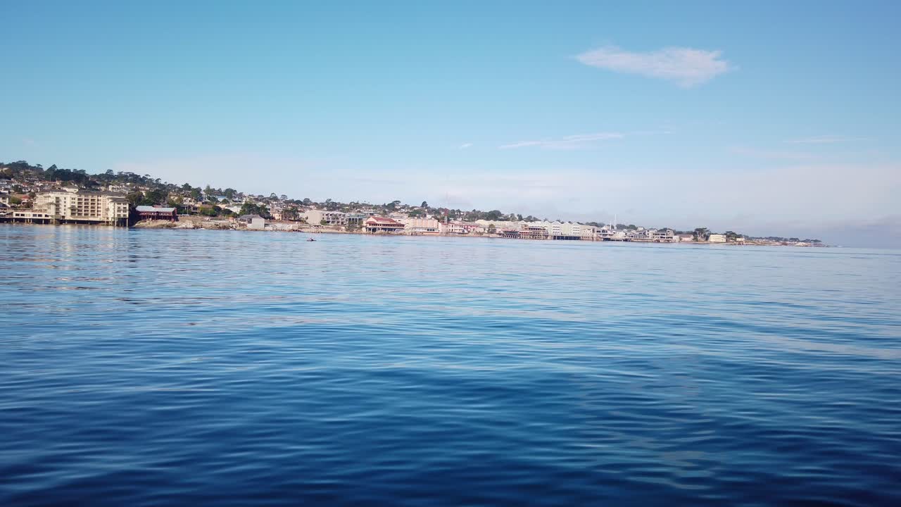 plano general del cardán de la fila de la fábrica de conservas desde un barco en movimiento en el océano frente a la costa de monterey, california