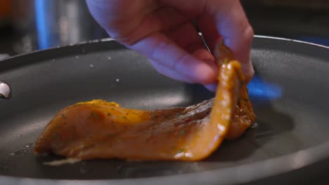 raw chinese chicken steak fillets being carefully placed by chef hand in hot frying pan with sizzling oil. cooking food photography footage 4k.