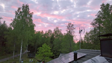 dramatic cloudy dusk sky and house roof full of photovoltaic cells - aerial view