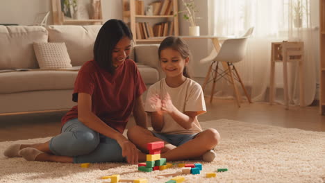 mother and daughter playing with building blocks at home