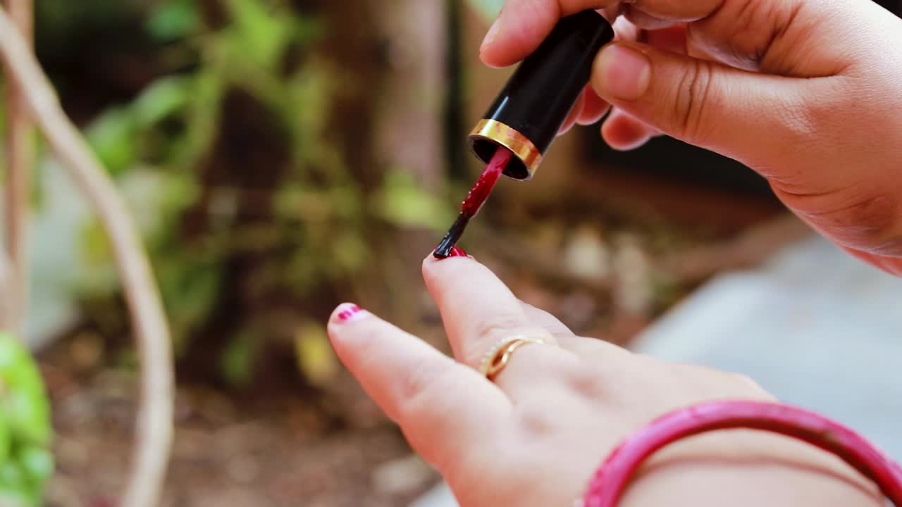 chica joven haciendo esmalte de uñas en las uñas en el día en detalles