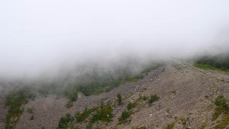 wide shot of fast cloudscapes covering hiking trails in rural landscape on top of mountain