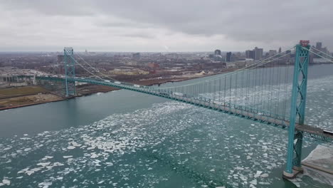 Vista-Aérea-De-Camiones-De-Transporte-Cruzando-El-Puente-Embajador-Sobre-El-Río-Detroit