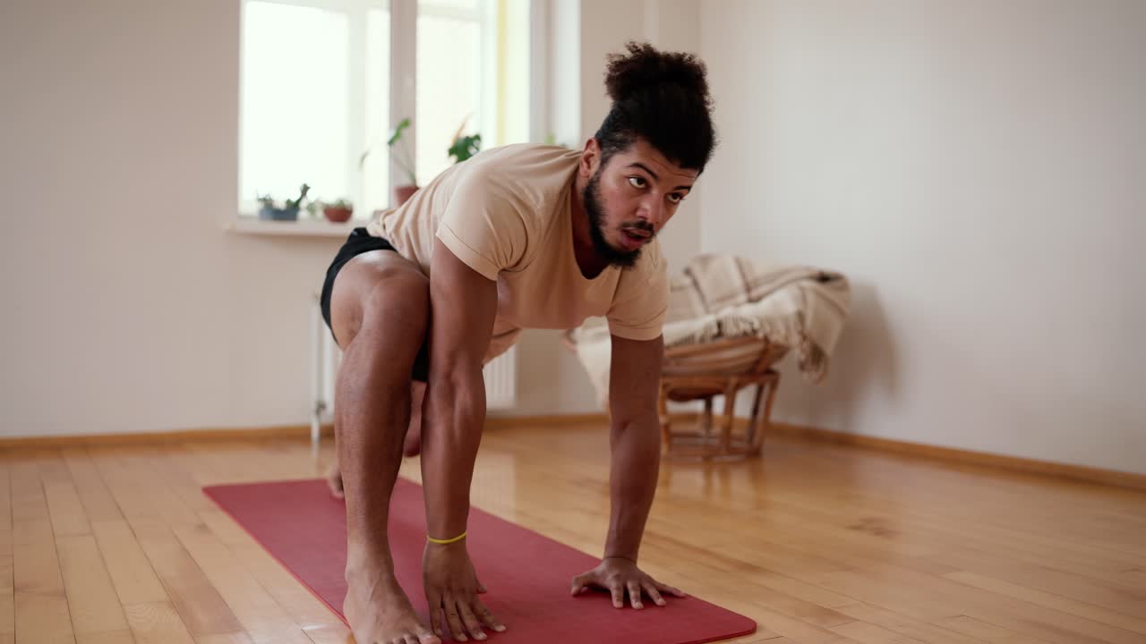 Young man performing legs stretch exercise at home