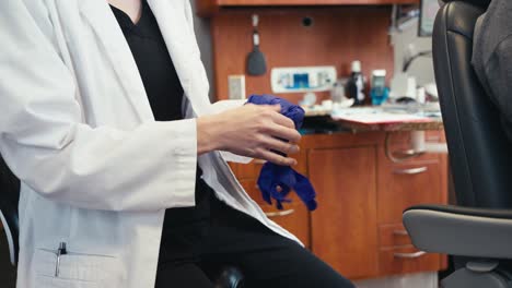 a dentist putting on blue rubber gloves preparing for a teeth cleaning