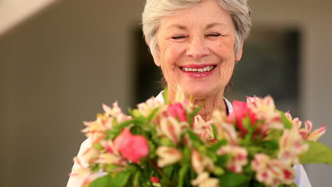 Mujer-Mayor-Oliendo-Ramo-De-Flores