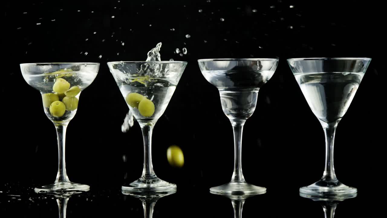 초록색 올리브 가 네 개 의  ⁇ 테일 컵 에 떨어지고 있다