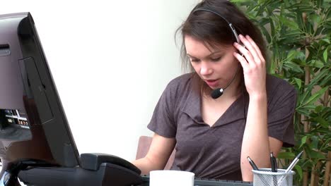 mujer concentrada con auriculares trabajando en una computadora