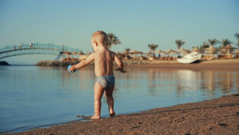 Niño-Activo-Jugando-Con-Juguete-Azul-En-La-Bahía-Del-Mar-De-Verano-En-Cámara-Lenta.