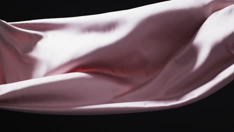 Animation-of-pink-fabric-blowing-with-copy-space-over-black-background