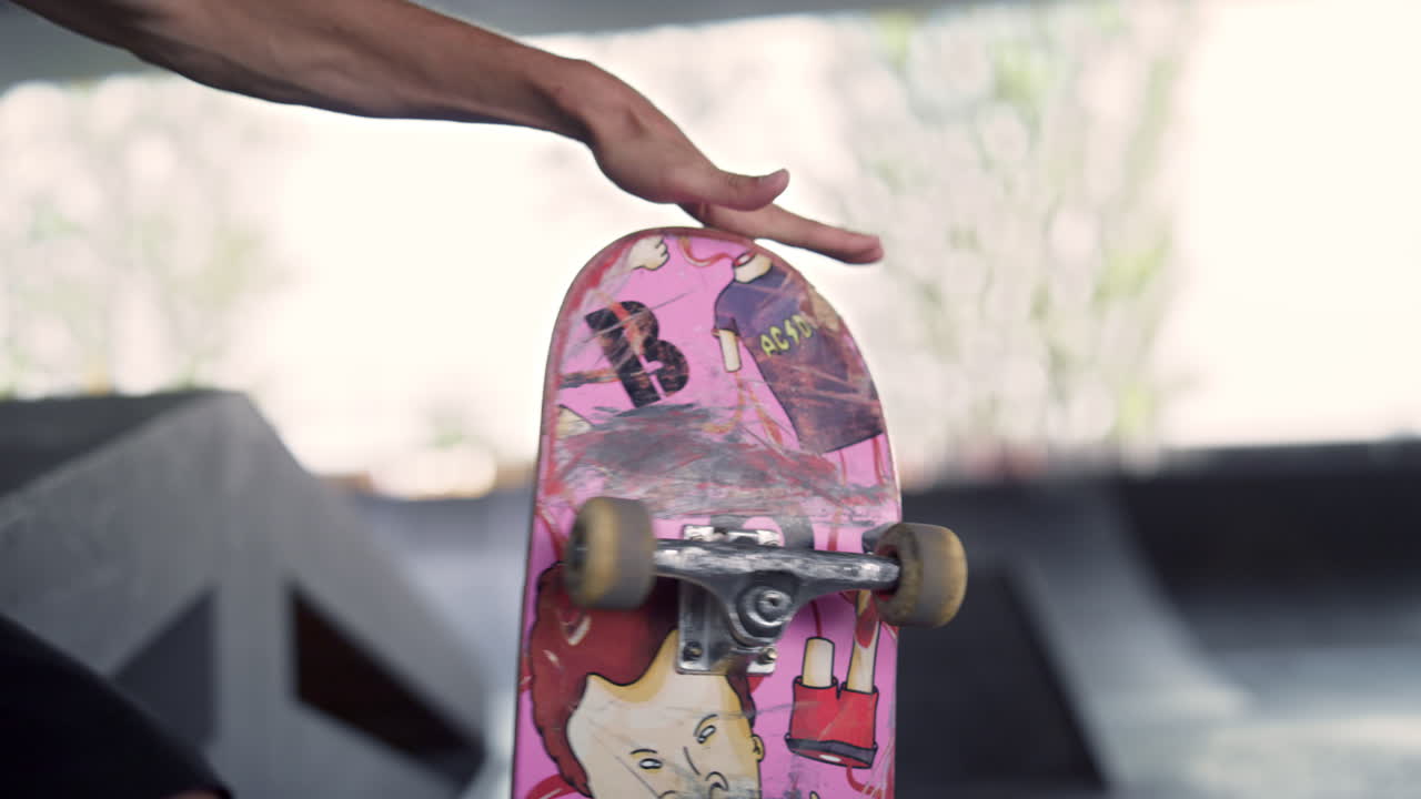 Young skater holding skateboard in hands at skate park. Unrecognizable man hand