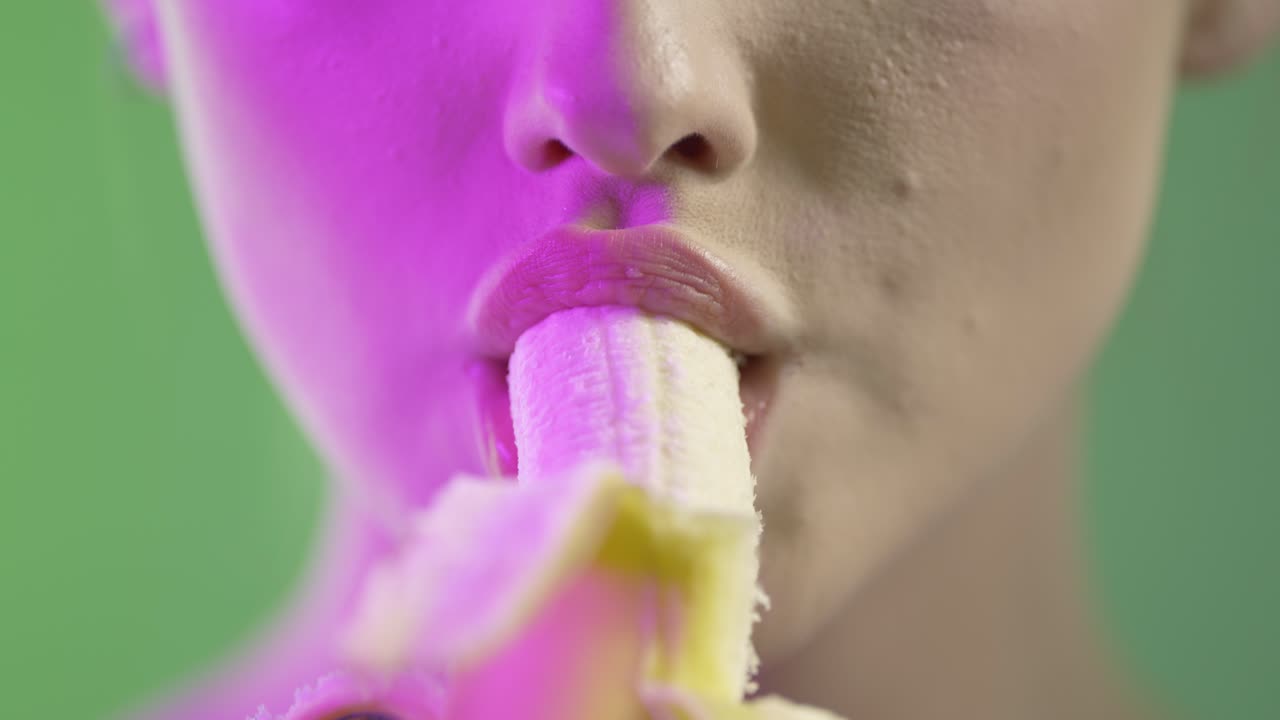 женщина съедает банан соблазнительно, близко до рта деталь