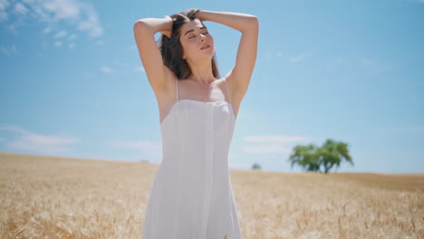 serene model warming sun at golden spikelets field horizon. sensual girl posing